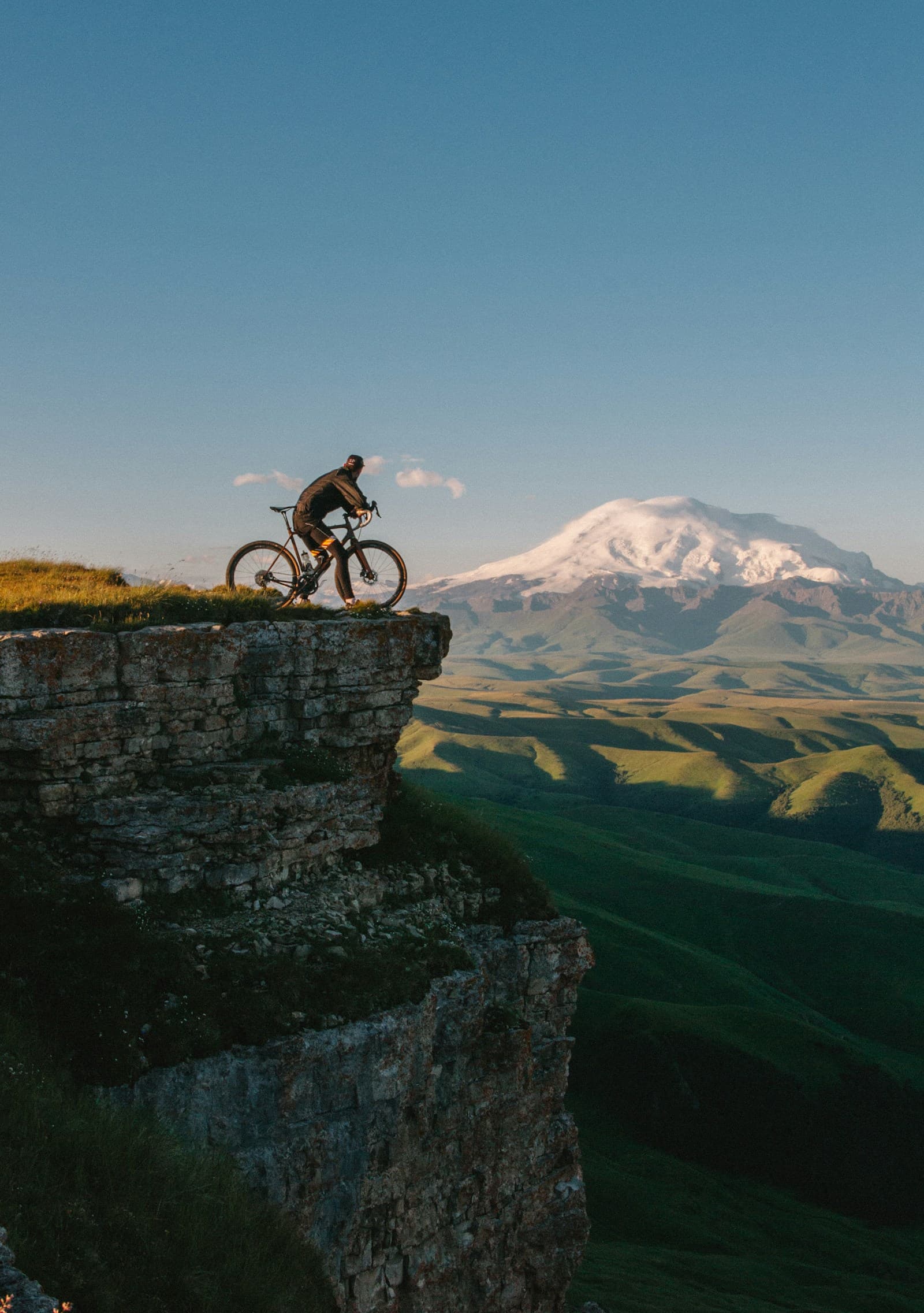 Two people riding gravel bikes along a coastal lane above the sea